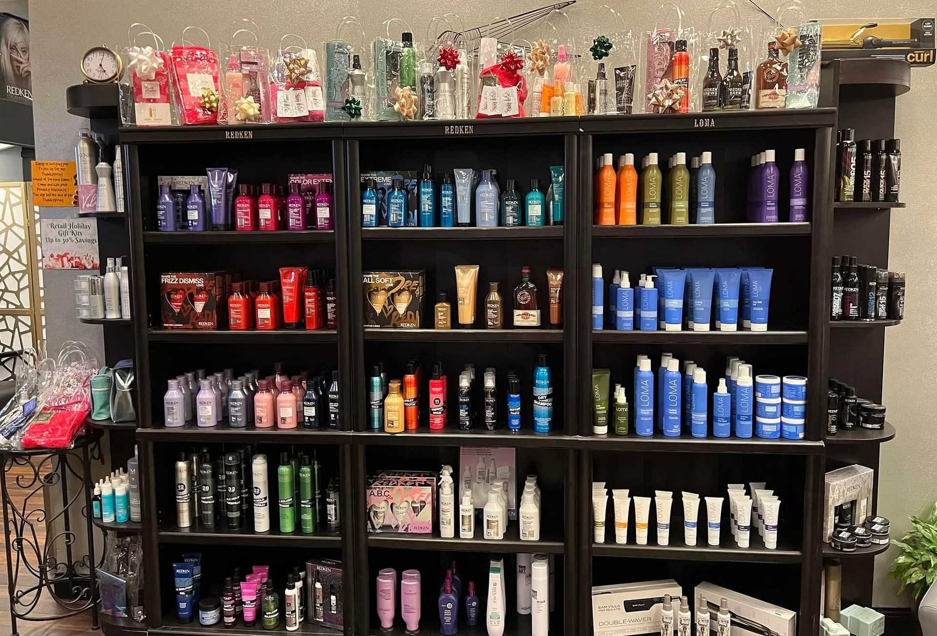 Salon product shelf with various haircare items, organized by brand and color on black shelves.